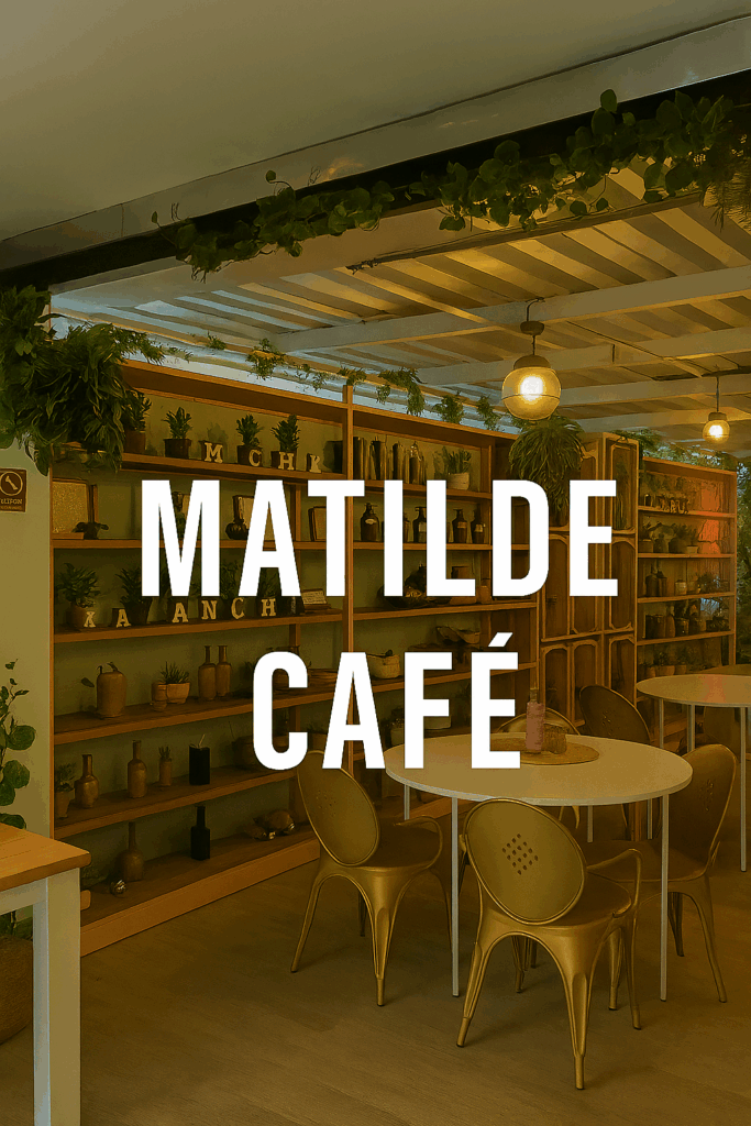 Bright café interior with pastel-pink shelving filled with potted plants and decorative items, golden chairs around a white round table, and hanging greenery overhead.