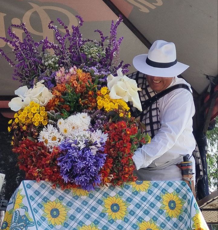 Flower farmer in Santa Elena crafting a traditional silleta for Feria de las Flores using fresh blooms and wooden frame