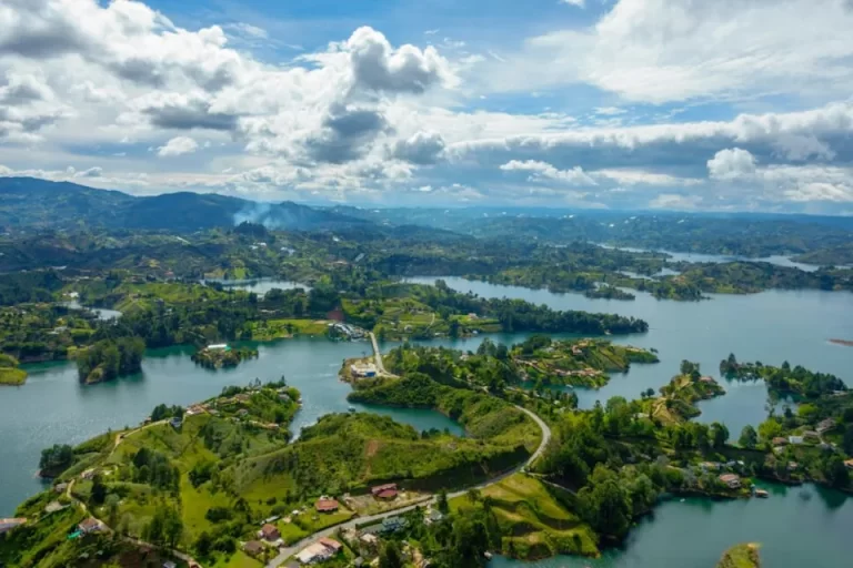 Aerial view of lush green Colombian landscapes, including rolling hills and dense forests, representing ethical and sustainable solo travel exploration in natural regions like Guatape, the Coffee Axis or Amazon.